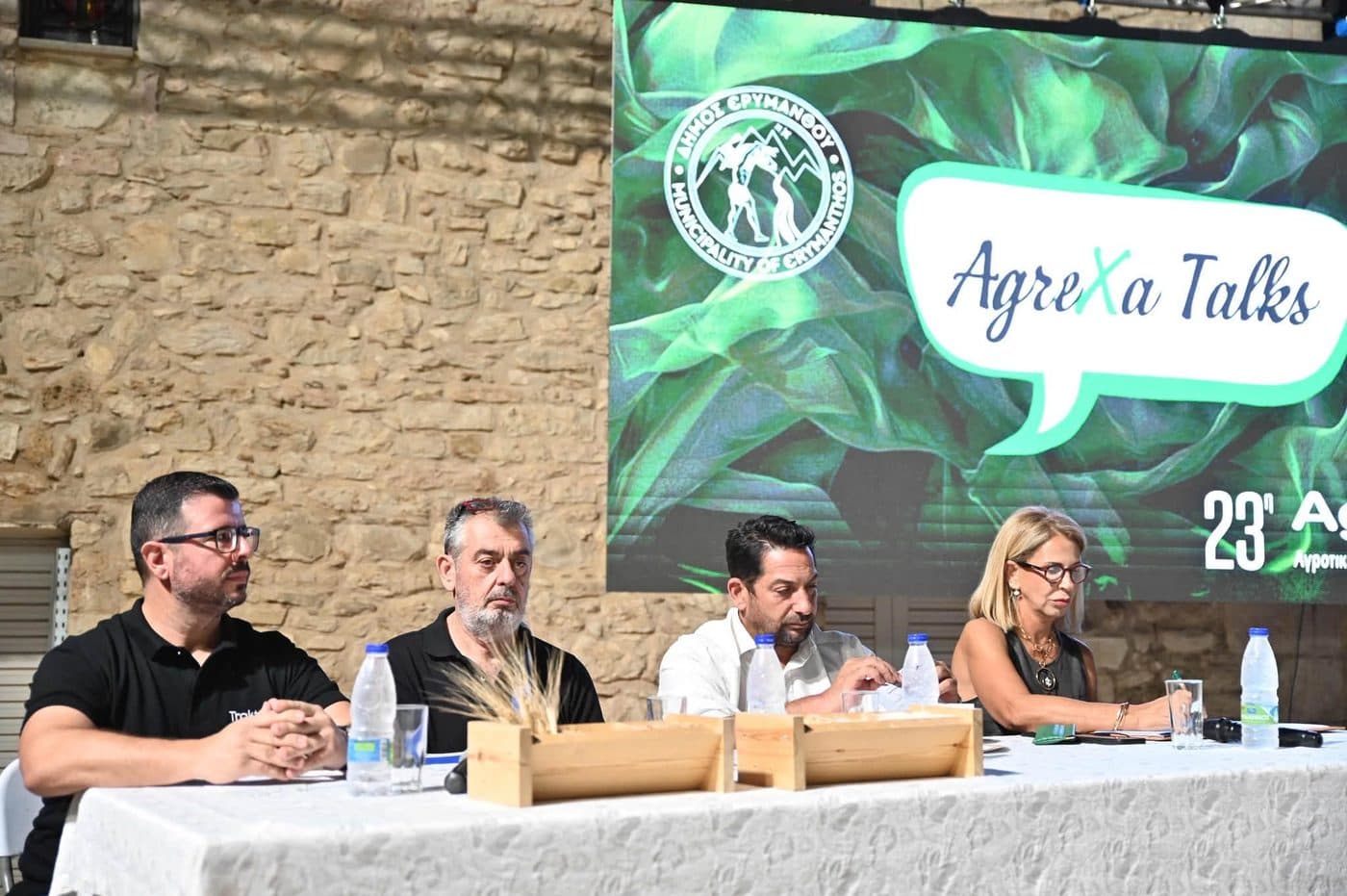 A member of the Trakterás team on a discussion panel, in front of a screen showing the AgreXa Talks logo